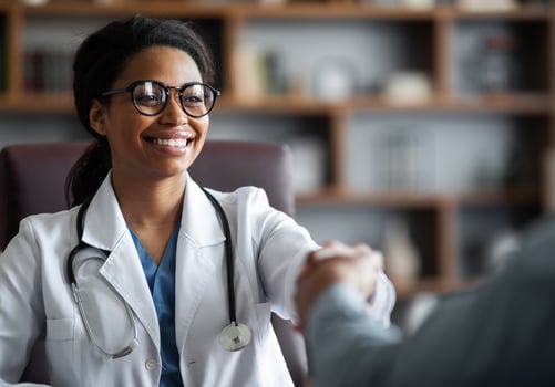 Closeup of friendly young african american lady doctor smiling and shaking male patient hand, cheerful black woman therapist greeting visitor at her clinic, outstretching hand, copy space photo