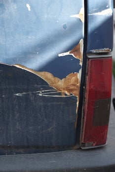 Old car with scratched paint and rust damage in urban area photo