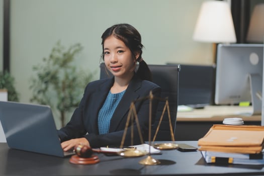 Asian woman in business suit sitting at desk with laptop photo