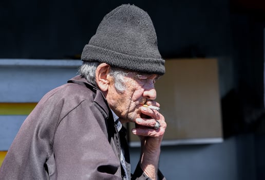 Elderly Russian village man lost in thought, smoking a cigarette in solitude, reflecting on life with a melancholic, distant gaze photo