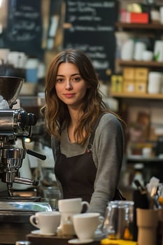 barista making coffee behind counter in cozy cafe surrounded by cups and machines. photo