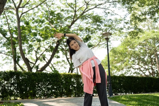 Wellness and vitality. Elderly individual engaged in side stretch outdoors photo