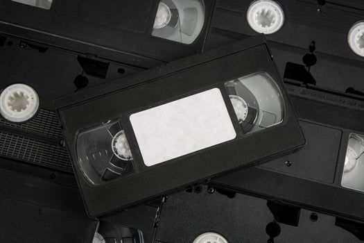 Stacked VHS tapes with a blank white label, black cassette. photo
