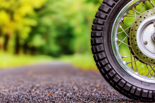 of a motorcycle tire on a gravel road, surrounded by lush greenery. photo