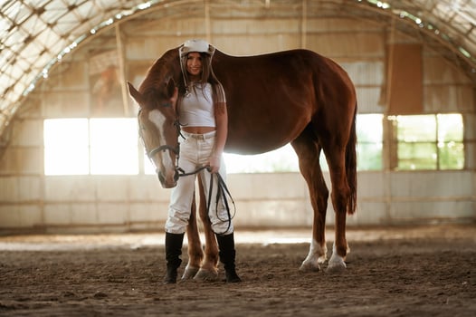 In the cowboy hat. Beautiful ,young ,woman is with horse indoors photo