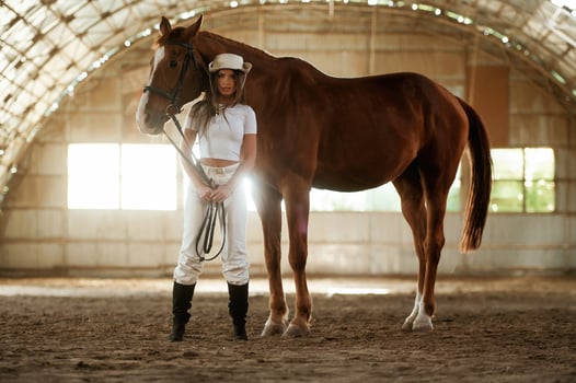 In the cowboy,, hat. Beautiful young woman is with horse indoors photo