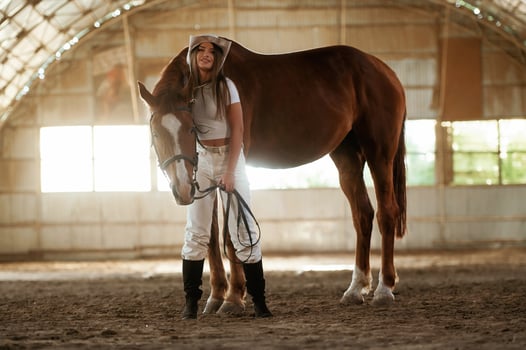 Standing and posing. Beautiful ,young woman, is with horse indoors photo