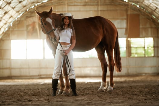 In the, cowboy hat.. Beautiful young woman is with horse indoors photo