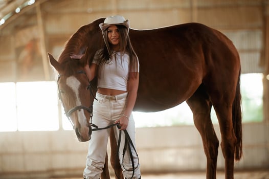 In ,,the cowboy hat. Beautiful young woman is with horse indoors photo