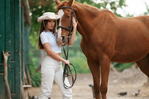 Woman ,is ,in hat, side view. With a horse outdoors photo