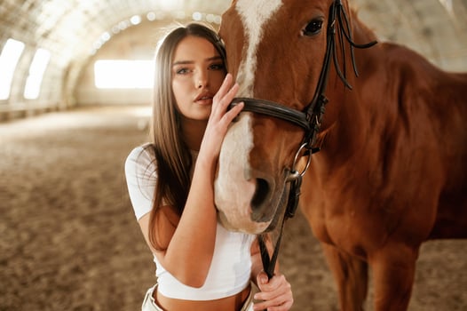 In white ,clothes, standing. Beautiful young woman is with horse indoors photo