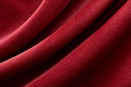 Red velvet fabric forming soft folds, luxurious texture close up photo