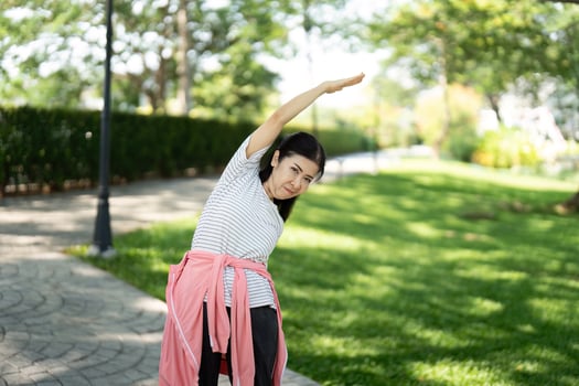 Wellness and fitness. Elderly woman stretching outdoors photo