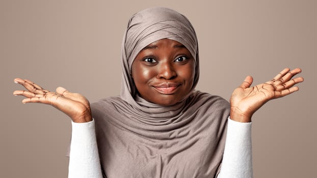 I Don't Know. Doubtful Black Muslim Lady In Hijab Shrugging Shoulders And Spreading Arms, Portrait Of Unsure African Religious Woman In Headscard Standing Over Light Studio Background, Copy Space photo