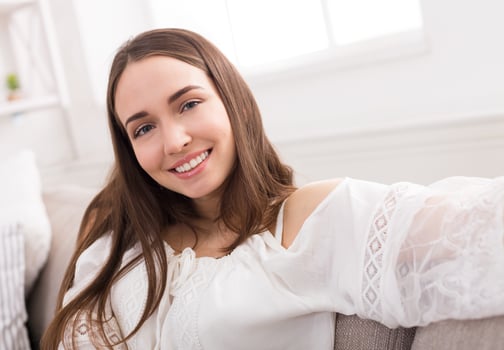Pretty smiling girl making selfie, long-haired brunette in white clothes, closeup indoors with copy space photo