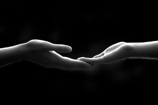 Two human hands gently reaching toward each other in darkness photo