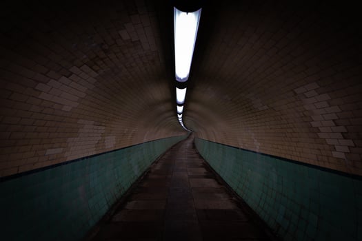 Long, dimly lit tunnel with brick walls and tiled wainscoting photo