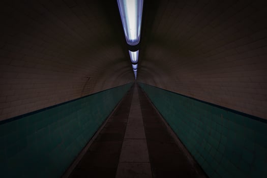 Empty pedestrian tunnel with turquoise tiles and lights illuminating the path photo