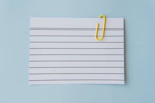 Minimal school paper concept with lined sheet and yellow paperclip on blue background symbolizing writing planning simplicity schoolwork education mood and creative organization for students photo