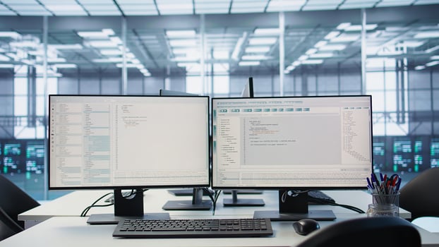 Computers in empty high tech data center establishment monitoring hardware energy consumption. PC monitors on desk used for checking potential system failures in server room, panning shot photo