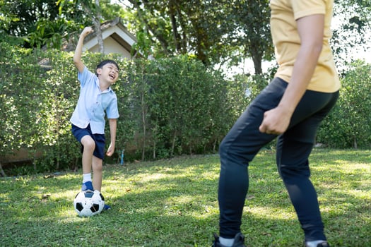 Activity. Young Boy Having Fun Kicking a Soccer Ball with Dad photo