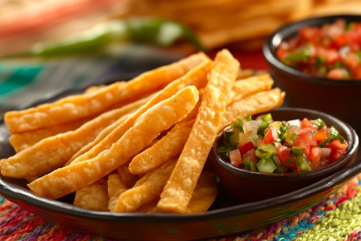 Enjoy crispy tortilla strips served with vibrant salsa alongside a variety of colorful Mexican snacks on a festive table photo