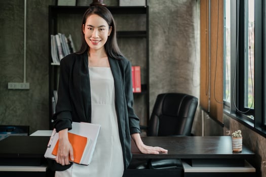 Professional woman in a stylish office setting, exuding confidence and success, holding documents. photo