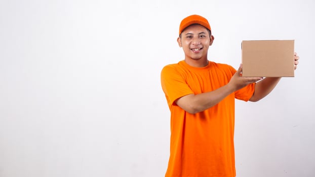 Asian deliveryman in orange t-shirt uniform with a package box parcel isolated on white background photo