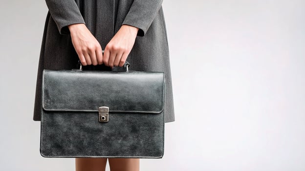 A woman in a gray dress holds a black briefcase photo