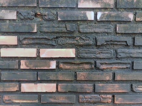 Textured gray wall appears aged and weathered with visible cracks, evoking sense of history and urban decay along street photo