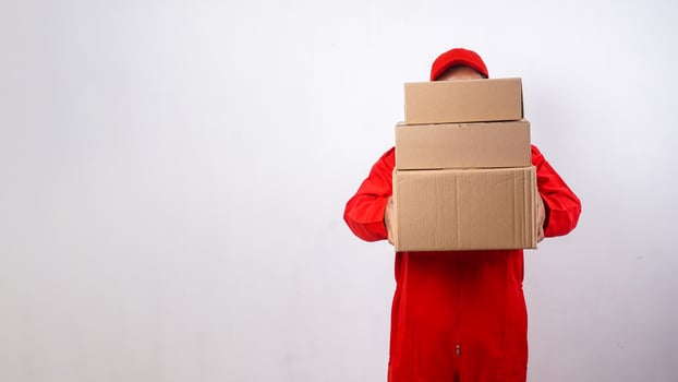 Delivery man in red uniform hide his face with package boxes parcel isolated on white background photo