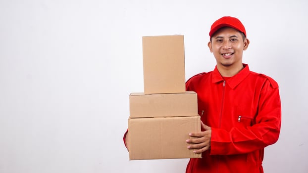 Delivery man in red uniform carrying stack of package boxes parcel isolated on white background photo