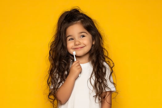 Little girl with a toothbrush on a yellow background. Oral hygiene. photo