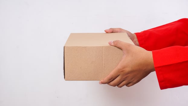 Close up of delivery man in red uniform holding a package box parcel to deliver to customer isolated on white background photo