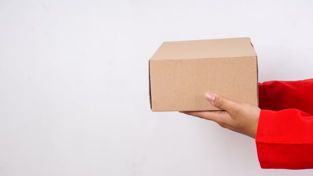 Close up of delivery man in red uniform with a package box parcel to deliver to customer isolated on white background photo