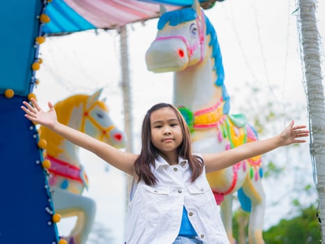 Happy Asian girl spinning on a carousel surrounded by bright lights and joyful atmosphere photo