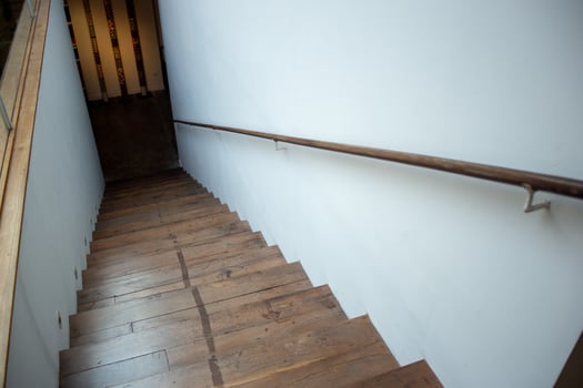 A sloping wooden staircase stairway going downward path photo