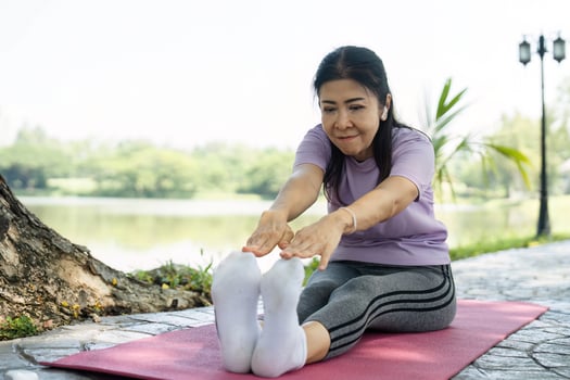 Wellness through Stretching. A woman practicing yoga outdoors by a serene lake. photo
