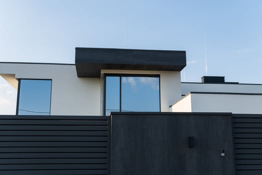 A contemporary house with a minimalist facade features large windows and a flat roof against a clear blue sky photo