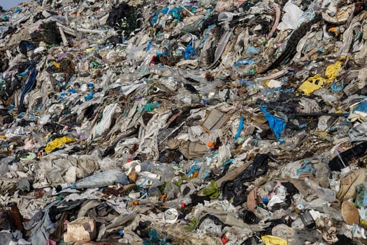 A vast pile of mixed waste is visible, showcasing discarded textiles, plastics, and debris. This landfill reflects ongoing environmental challenges photo
