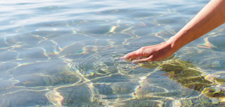 A woman's hand touching the sea water. Banner. Copy space. Selective focus. photo