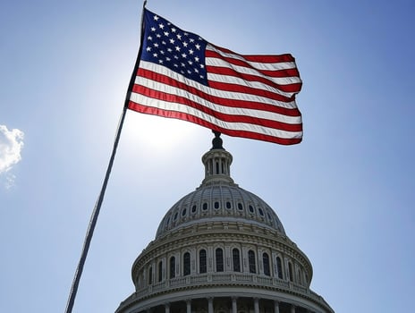 US flag waves over Capitol building during clear day photo