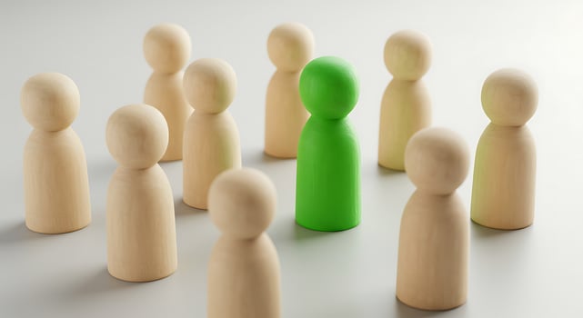Green Peg Among Beige Wooden Figures on White Background photo