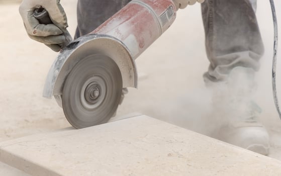 man in grey work clothes and helmet cutting marble piece during construction photo