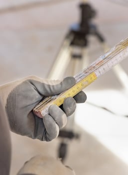 Craftsman in dusty glove holding a folded rule against rotary laser level photo