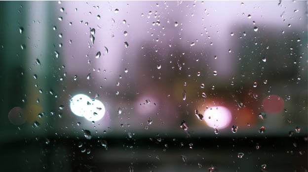 Raindrops on glass create a blurred urban view during a rainy evening photo