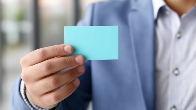 Individual holds a blank business card in a professional setting during a networking event photo