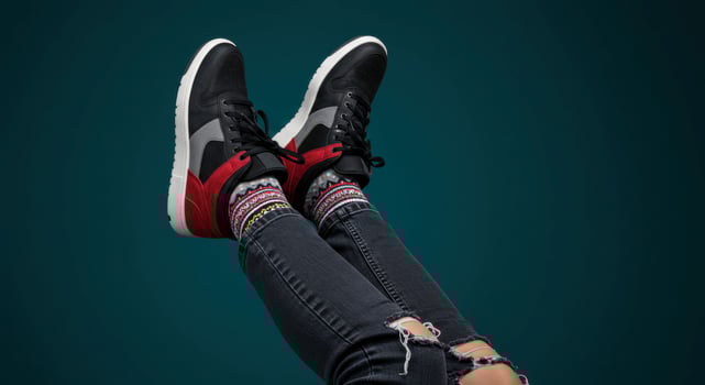 Pair of legs wearing ripped jeans patterned socks and high top sneakers photo