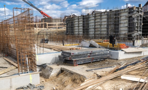Construction Site With Foundation Work Underway in an Urban Area Surrounded by Machinery and Materials During a Clear Day photo