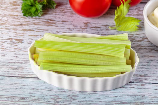 Celery sticks in a bowl with tomatoes and herbs on a wooden table photo